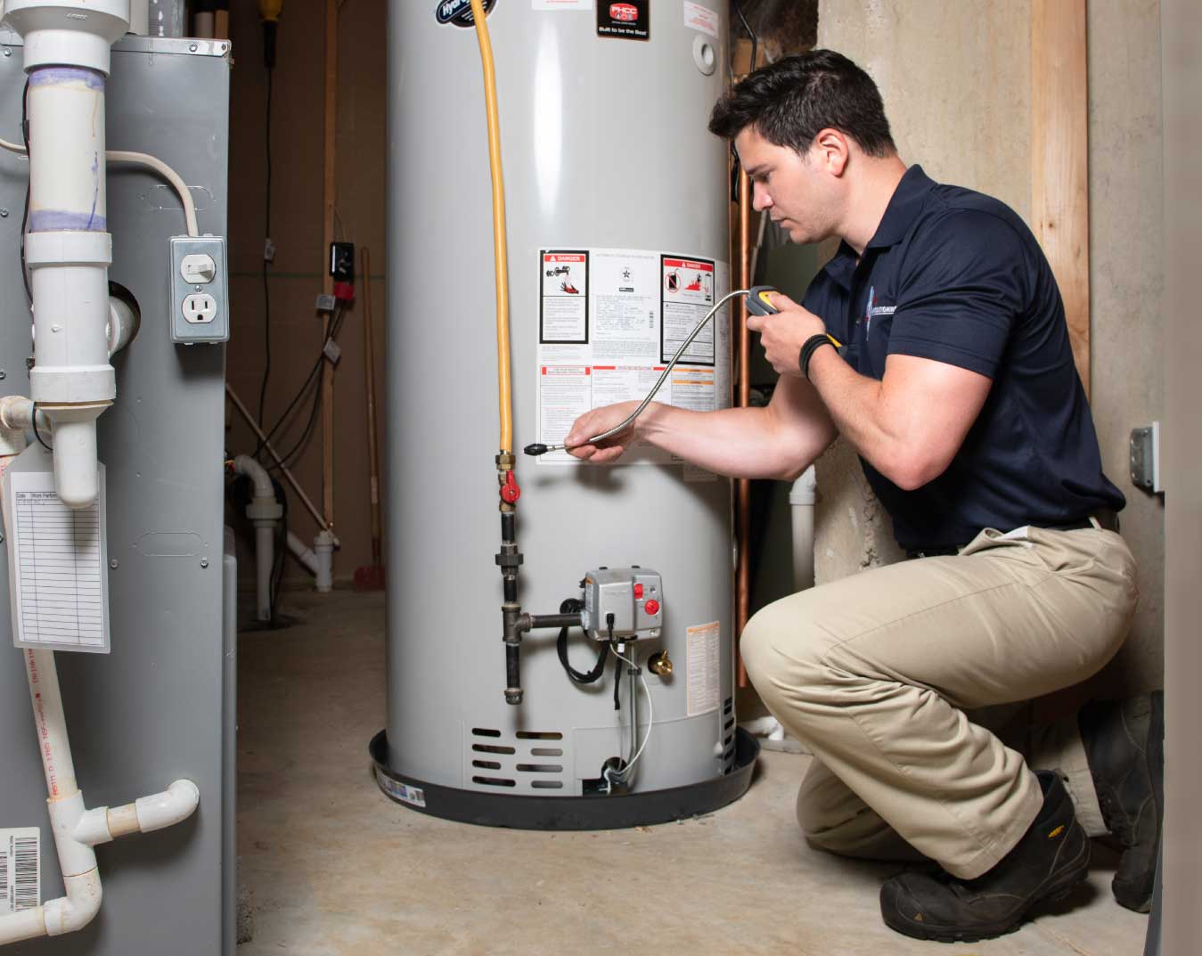 Plumber checking gas supply line and venting connections during a water heater installation in Ventura County